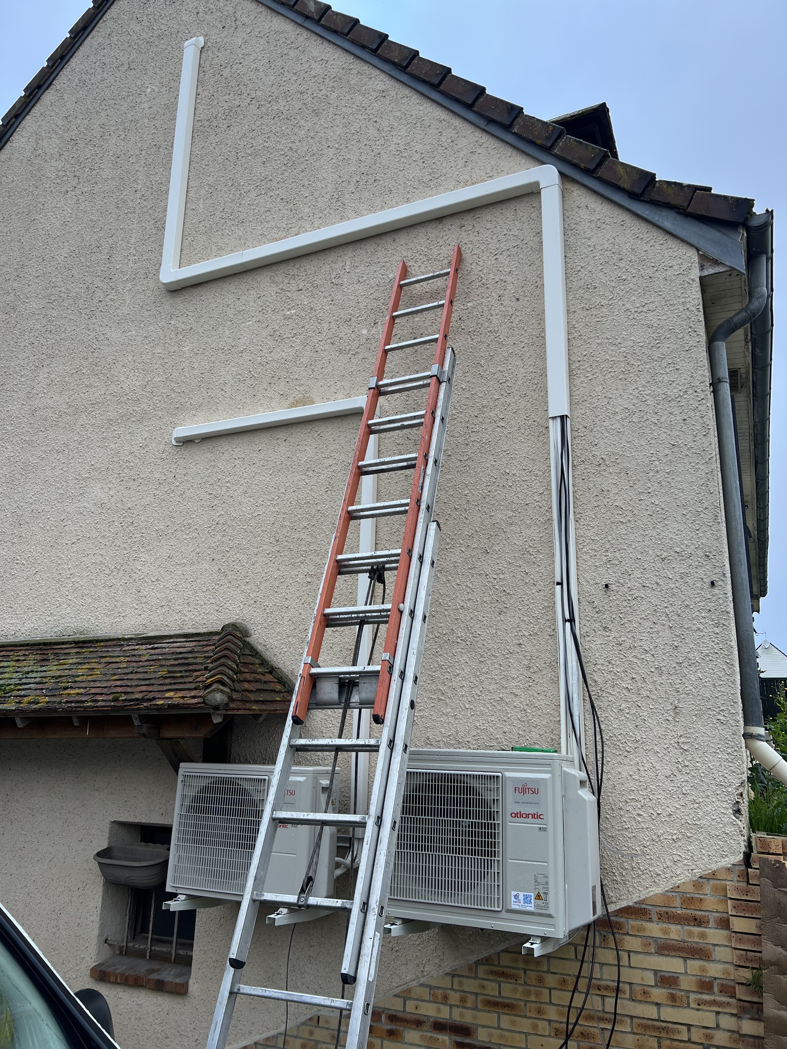 Installation d'une unité extérieure de pompe à chaleur sur la facade d'une maison à Saint Leu La Forêt